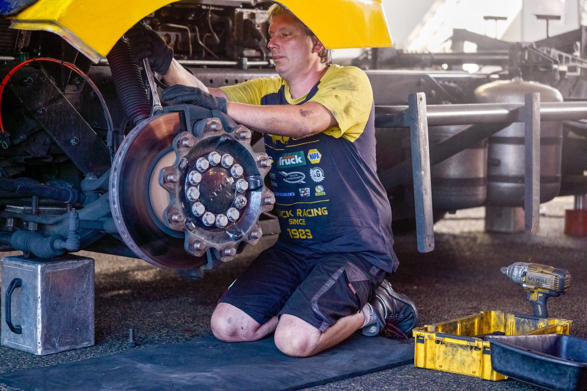 Un mécanicien de la Team Robineau, à genoux, intervient sur le moyeu et les freins d’une roue du camion #8 à Magny-Cours